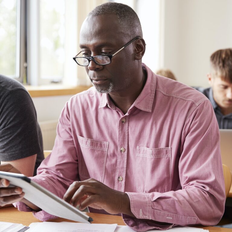 Mature Student Using Digital Tablet In Adult Education Class